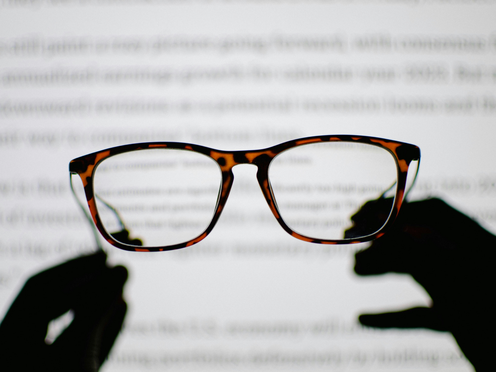 Blurry text seen through a pair of glasses, symbolizing the clarity required in science to maintain trust